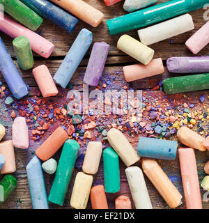Collection of rainbow colored artistic pastel crayons with pigment dust on old wooden desk. Stock Photo