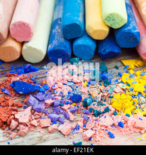 Pile of crushed chalk closeup and rainbow colored pastel crayons on background. Selective focus. Stock Photo