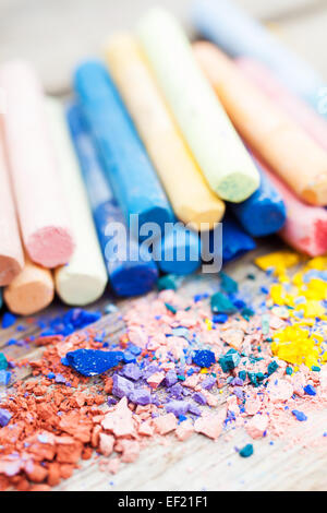 Pile of crushed chalk closeup and rainbow colored pastel crayons on background on wooden desk. Selective focus. Stock Photo