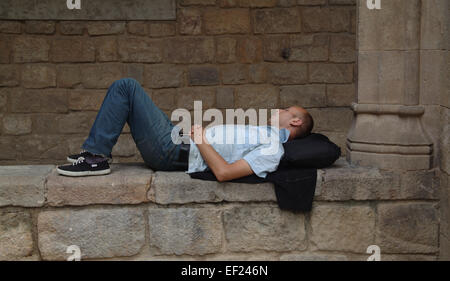 Man lying on wall of old building in historic neighbourhood of El Raval, Barcelona Stock Photo