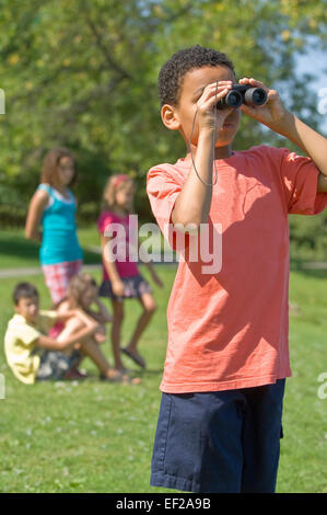 Boy looking through binoculars at the park Stock Photo