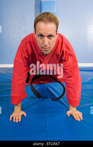 A man in a gym wearing karategi doing push ups Stock Photo