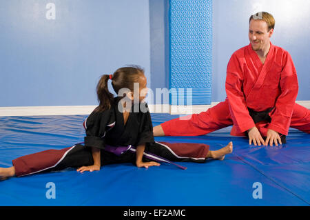 A man in a gym doing karate with a young girl Stock Photo