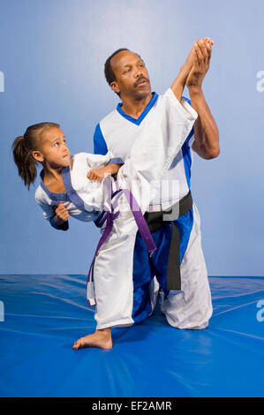 A man in a gym doing karate with a young girl Stock Photo