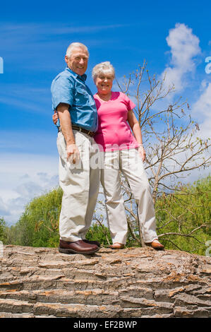 Senior couple at park on fallen tree Stock Photo