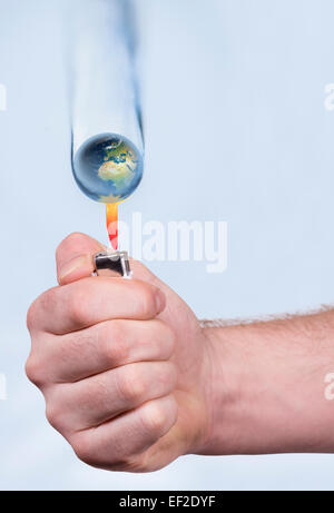 Hand holding lighter below the earth shape  droplet. Stock Photo