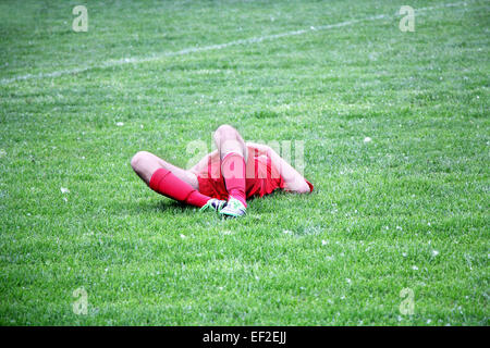 Injured Football or Soccer Player Lying On The Ground Stock Photo