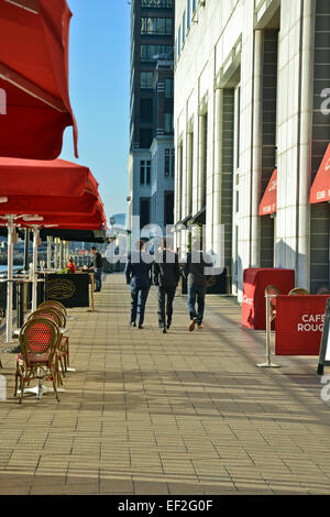 Back view of Business men walking past outside seated cafe area at Canary Wharf London UK Stock Photo