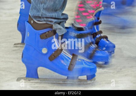 Blurred lower body shoot of Mother and child ice skaters on out door ice rink Stock Photo