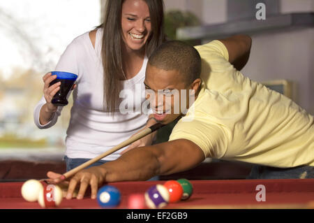 Man playing pool while female friend distracts him Stock Photo