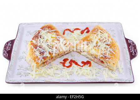 Stuffed pizza cut in half decorated with grated cheese on a plate, isolated on white background Stock Photo