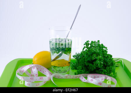 Glass of lemon and parsley on a green tray shot against white background Stock Photo
