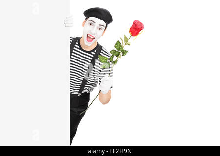 Mime artist holding a red rose behind a panel isolated on white background Stock Photo