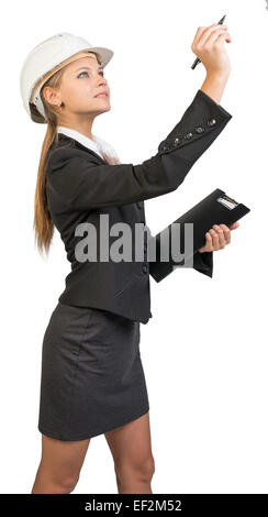 Businesswoman wearing hard hat, holding clipboard, drawing or wr Stock Photo