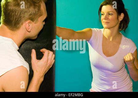 Two people using punching bag Stock Photo