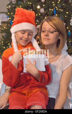 Woman giving a young girl a gift at Christmas Stock Photo