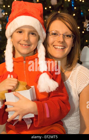 Woman giving a young girl a gift at Christmas Stock Photo