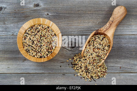 Top view angled shot of a wooden bowl and scoop filled with whole grain rice on rustic wood. Stock Photo