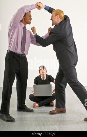 Two businessmen fighting in front of annoyed woman Stock Photo
