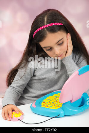 Little girl playing on a toy laptop computer Stock Photo