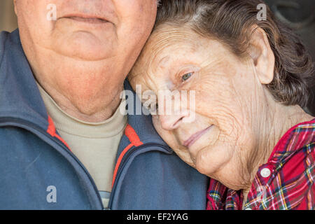 A 70 something year old, Latin woman leans her head against husbands shoulder; she seems sad. Stock Photo