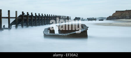 Broken Sea Defences and the remains of a war time look out at Happisburgh in Norfolk England Stock Photo