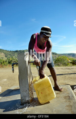 Young woman filling a canister at a water supply well, Ridore, La Vallee, Sud-Est Department, Haiti Stock Photo