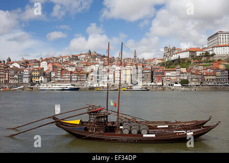 City of Porto in Portugal. Rabelo traditional Portuguese cargo boat with Port wine barrels on Douro river and old city skyline. Stock Photo