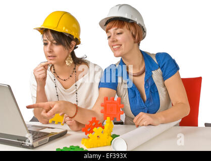 Two women wearing hardhats and looking at laptop Stock Photo