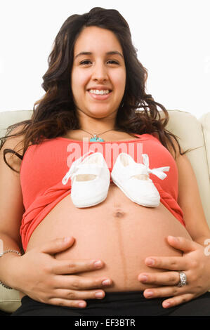 Baby shoes on pregnant woman's belly Stock Photo
