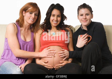Pregnant woman sitting on couch with her friends Stock Photo