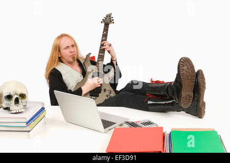 Guitar playing sitting at desk Stock Photo