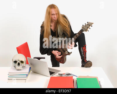 Long haired guitarist playing guitar instead of working Stock Photo