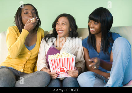 Three friends eating popcorn Stock Photo
