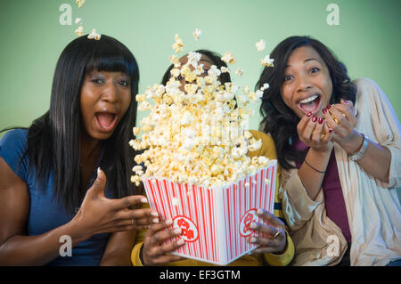 Three friends eating popcorn Stock Photo