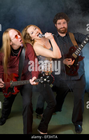 Woman singing with two guitar players Stock Photo
