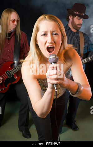 Woman singing with two guitar players Stock Photo