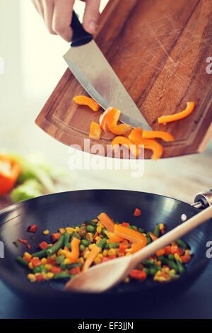 close up of male hand adding peppers to wok Stock Photo