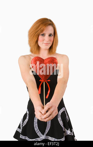 Redheaded woman holding heart on a stick Stock Photo