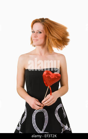 Pretty red haired woman holding heart on a stick Stock Photo