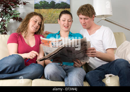 Three friends reading newspaper together Stock Photo