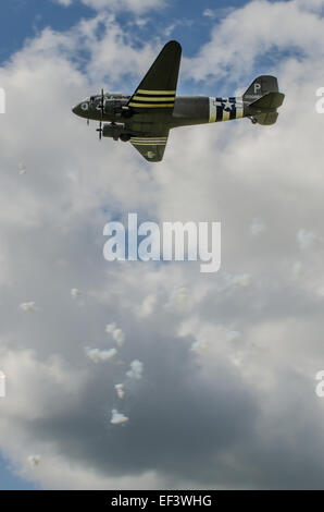 A USAAF marked Douglas DC3 Dakota flies through puffs of simulated anti-aircraft fire during a D-Day re-enactment at Shoreham airshow 2014 Stock Photo