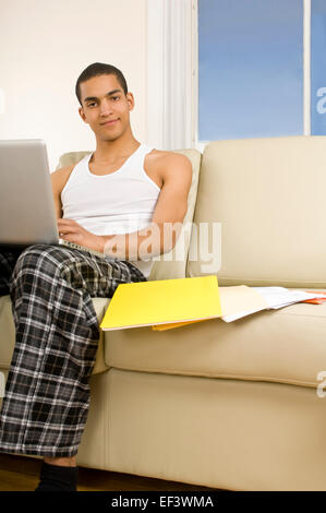 Man working on laptop while sitting on couch Stock Photo