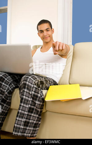Man pointing his finger while sitting on couch with laptop Stock Photo