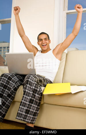 Happy man sitting on couch with laptop Stock Photo