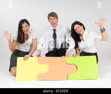 Three people sitting on floor putting puzzle pieces together Stock Photo