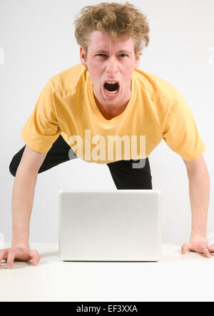 Angry man jumping up from his desk Stock Photo
