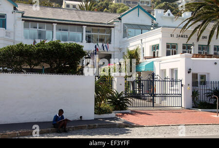 Child reading a book and sitting on the street in St James which is an exclusive coastal suburb of Cape Town Stock Photo