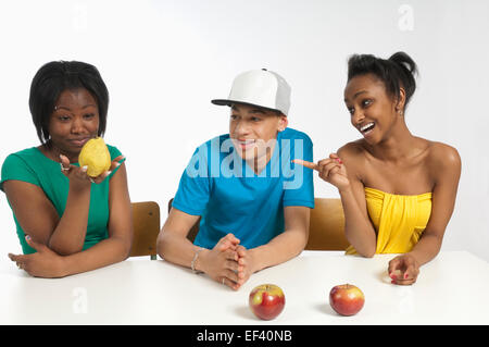 Two young people laughing as their friend examines a pear Stock Photo