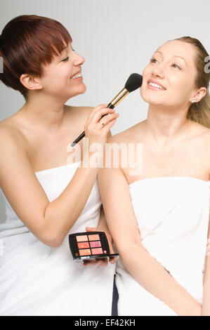 Woman putting blush on another woman Stock Photo